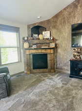 Unfurnished living room with carpet flooring, a fireplace, and a textured ceiling