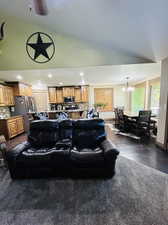 Living room featuring lofted ceiling, dark wood-type flooring, and a notable chandelier