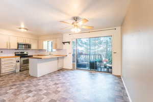 Kitchen with backsplash, kitchen peninsula, stainless steel appliances, and ceiling fan