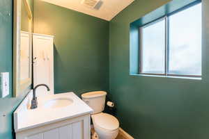 Bathroom with vanity, toilet, a wealth of natural light, and a textured ceiling