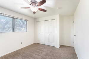 Unfurnished bedroom with carpet flooring, ceiling fan, and a closet