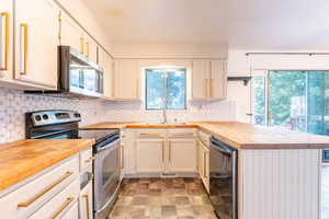 Kitchen with tasteful backsplash, stainless steel appliances, butcher block counters, and sink