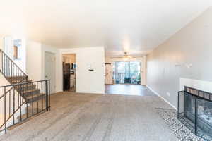 Living room with a tiled fireplace, ceiling fan, and carpet floors