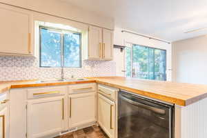 Kitchen featuring dishwasher, butcher block countertops, plenty of natural light, and sink