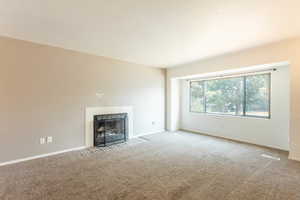 Unfurnished living room featuring carpet flooring and a tile fireplace