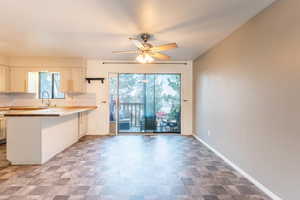 Kitchen featuring tasteful backsplash, kitchen peninsula, sink, ceiling fan, and butcher block counters