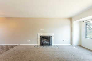 Unfurnished living room featuring a fireplace and carpet