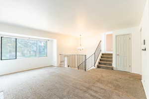 Carpeted spare room with an inviting chandelier