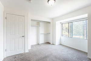 Unfurnished bedroom with light colored carpet and a closet