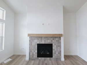 Interior details with a tiled fireplace and hardwood / wood-style floors