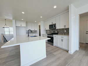 Kitchen featuring light wood-type flooring, sink, appliances with stainless steel finishes, and white cabinetry