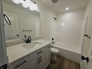 Full bathroom with vanity, toilet, hardwood / wood-style floors, and shower / washtub combination