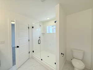 Primary bathroom with quartz counters, light marble finish floors and walk-in shower