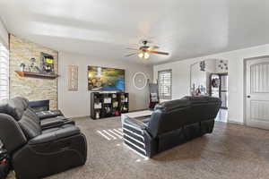 Living room with a fireplace, carpet flooring, and ceiling fan