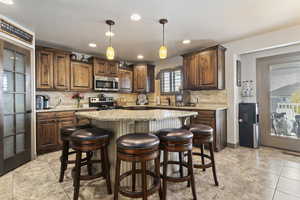 Kitchen featuring a center island, appliances with stainless steel finishes, decorative backsplash, light tile patterned floors, and hanging light fixtures