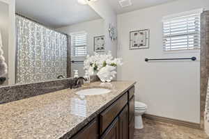 Bathroom with tile patterned floors, toilet, vanity, and a wealth of natural light