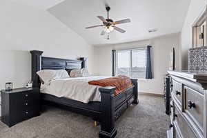 Carpeted bedroom featuring ceiling fan and vaulted ceiling