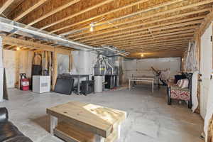 Basement featuring water heater, heating unit, and refrigerator