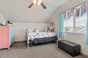 Carpeted bedroom with ceiling fan and lofted ceiling