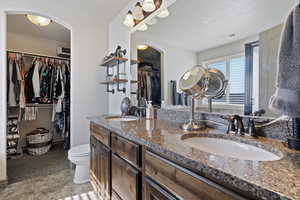 Bathroom featuring tile patterned flooring, toilet, and double sink vanity