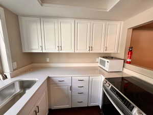 Kitchen with crown molding, stainless steel electric range oven, sink, and white cabinets