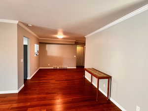 Unfurnished room with crown molding and dark wood-type flooring