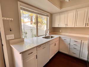 Kitchen featuring a healthy amount of sunlight, white cabinets, white dishwasher, and sink