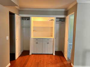 Interior space featuring wood-type flooring, ornamental molding, and two closets