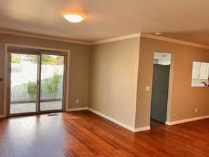 Empty room with crown molding and dark hardwood / wood-style flooring