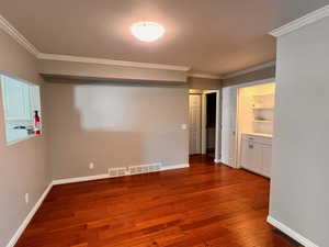 Unfurnished room featuring built in features, hardwood / wood-style floors, and ornamental molding