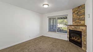 Unfurnished living room with a fireplace, a textured ceiling, and carpet floors