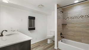 Full bathroom featuring vanity, toilet, hardwood / wood-style floors, and tiled shower / bath