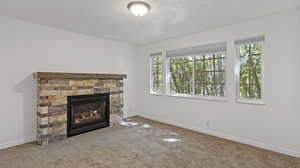 Unfurnished living room featuring a fireplace, a textured ceiling, and carpet floors