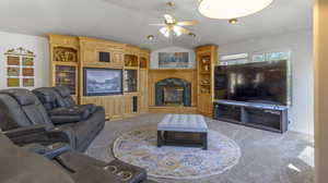 Living room with ceiling fan, carpet floors, a fireplace, and vaulted ceiling