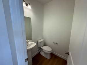 Bathroom with toilet, wood-type flooring, and sink