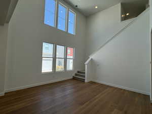 Unfurnished living room with a high ceiling and dark hardwood / wood-style floors