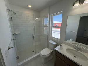 Bathroom featuring tile patterned flooring, an enclosed shower, toilet, vanity, and a textured ceiling