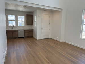 Kitchen with a textured ceiling, tasteful backsplash, sink, hardwood / wood-style flooring, and stainless steel dishwasher