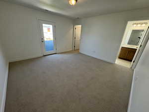 Unfurnished bedroom featuring light colored carpet, a textured ceiling, and ensuite bath