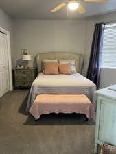 Carpeted bedroom featuring ceiling fan and a closet