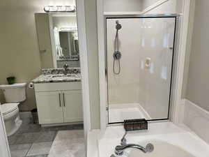 Full bathroom featuring toilet, shower with separate bathtub, and vanity