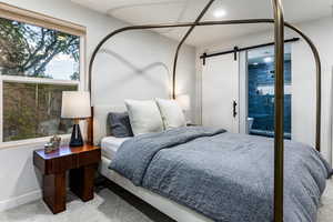 Carpeted bedroom with a barn door and access to bathroom