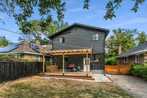 Rear view of property featuring a pergola and a deck