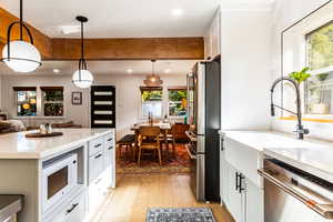 Kitchen featuring appliances with stainless steel finishes, light hardwood / wood-style floors, white cabinetry, pendant lighting, and a kitchen island