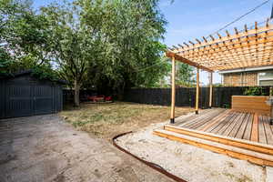 View of yard with a pergola, a wooden deck, and a shed