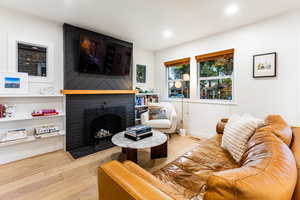 Living room with light hardwood / wood-style floors and a brick fireplace