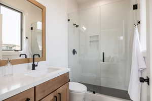 Bathroom with vanity, toilet, and a shower with shower door