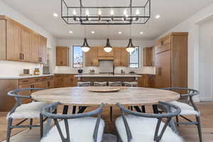 Kitchen with hardwood / wood-style floors, backsplash, decorative light fixtures, a kitchen island, and an inviting chandelier