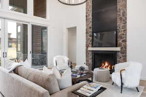 Living room with a stone fireplace, a towering ceiling, and hardwood / wood-style floors