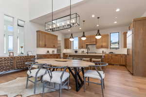 Kitchen featuring light wood-type flooring, a chandelier, a center island with sink, hanging light fixtures, and stainless steel built in refrigerator